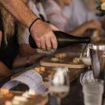a person pouring a bottle of wine on a table