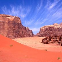a car driving through the desert with cliffs and a red sand