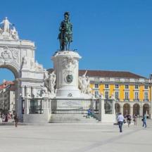 eine Statue vor einem Gebäude, um das herum Menschen laufen