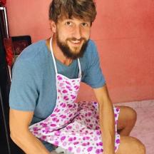 a man in apron sitting on the floor in a kitchen