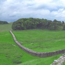 a large green field with a stone wall