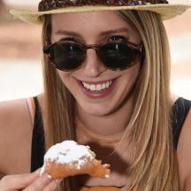 a woman wearing a hat and holding a pastry