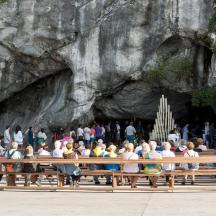 a group of people sitting on a bench in front of a cave