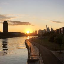 ein Sonnenuntergang über einem Fluss mit einer Stadt im Hintergrund