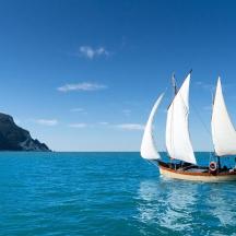 a sail boat with white sails in the ocean