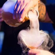 eine Person gießt ein Getränk in ein Glas