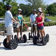 a group of people riding segways on a sidewalk