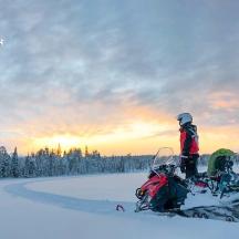 une personne debout à côté d'une motoneige dans la neige