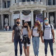 four people wearing masks standing in front of a building
