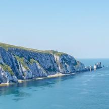 a large cliff in the ocean with boats in the water