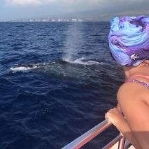 a man and a woman looking at a whale in the water