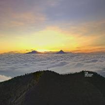 una vista di una montagna con il sole che tramonta sulle nuvole