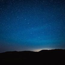 a starry night with a silhouette of a mountain