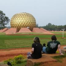 a group of people sitting on a rock looking at a large sphere