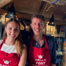 a man and a woman wearing aprons in a kitchen