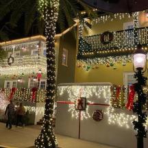 a building covered in christmas lights with people walking past it
