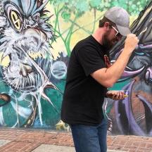 a man standing in front of a wall with a mural