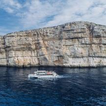 una barca in acqua vicino a una grande formazione rocciosa