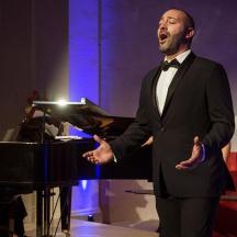 a man in a tuxedo standing next to a piano