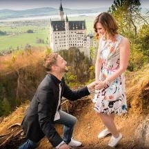 a man and a woman standing on a hill with a castle