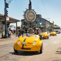 a man riding in a yellow car on a street