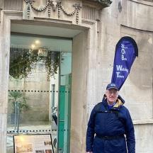 a man standing in front of a building with a surfboard
