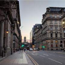 a city street with buildings and people walking down the street