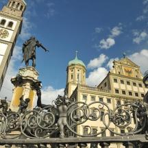 una statua di fronte a un edificio con una torre dell'orologio