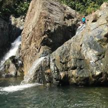 seseorang yang berdiri di atas batu berhampiran air terjun