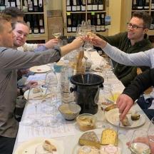 un grup de persones assegudes al voltant d'una taula amb copes de vi