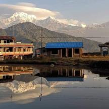 a group of buildings next to a body of water with mountains