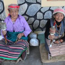 two older women sitting on benches holding torches