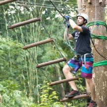 a man on a zip line in the forest