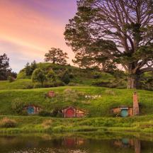 a small house on a hill next to a pond