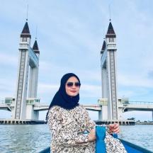 a woman standing in a boat in front of a bridge