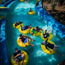 Un grupo de personas se deslizan en flotadores por una piscina en un parque acuático.