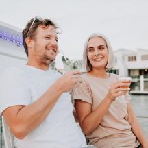 ein Mann und eine Frau halten Getränke auf einem Boot