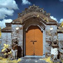 una porta di legno con due statue di fronte a un lago