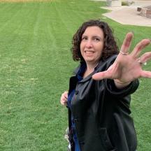 a woman standing in a field with her hand in the air