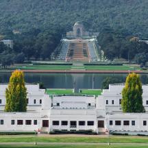 ein weißes Gebäude mit Bäumen vor einem Gewässer