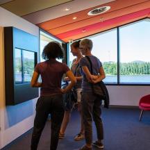 Eine Gruppe von Menschen steht in einem Raum und schaut auf eine Wand