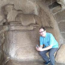a man sitting in front of a statue with his cell phone