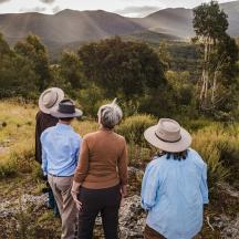 a group of people standing on a hill looking at the mountains
