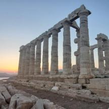 an ancient temple with columns at sunset