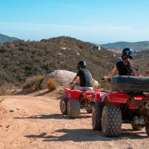 a group of people riding atvs on a dirt road