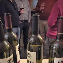 a group of people standing around three bottles of wine