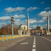 a bridge over a street with columns and a city