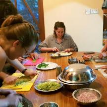 a group of people sitting around a table preparing food