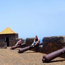 a man and a woman sitting on cannons on a pier