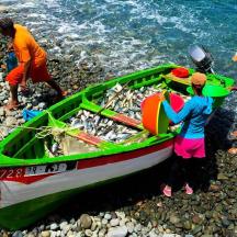 a group of people working on a boat on the shore